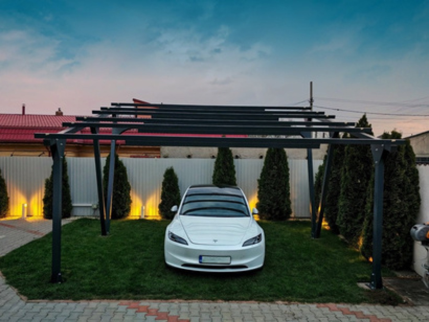Carport HelioPort în curtea unei case, iluminat seara